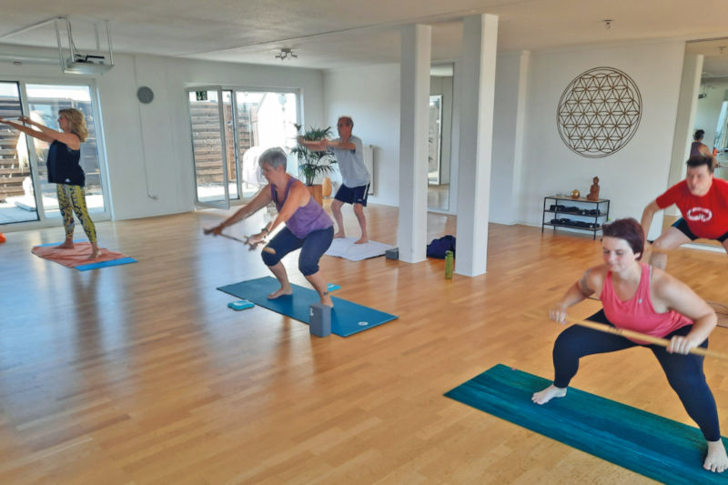 Gruppe beim angeleiteten Rückentraining auf Gymnastikmatten im Fitnessstudio